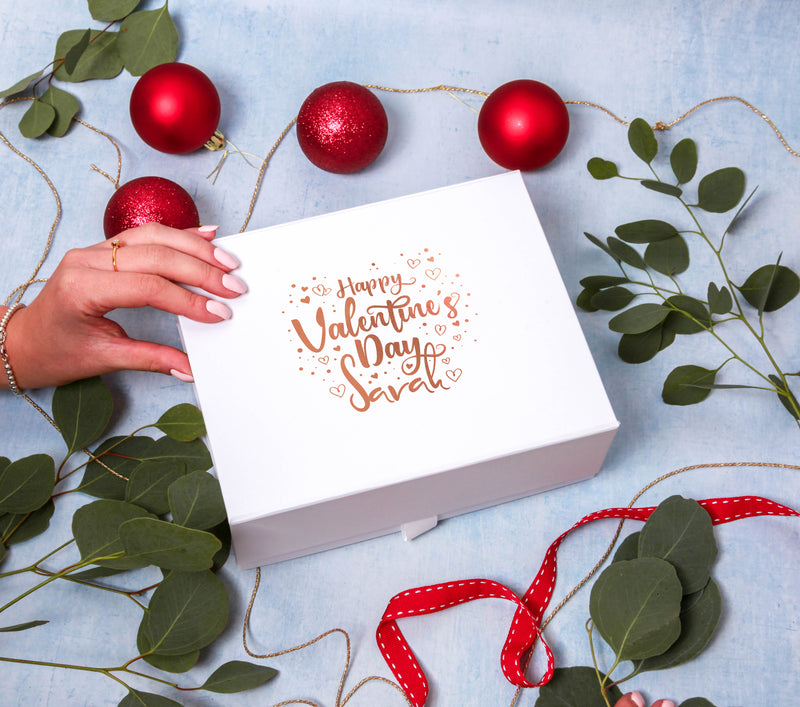 a woman's hand holding a valentine's day box