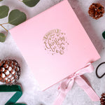 a pink box with a pink ribbon and pine cones