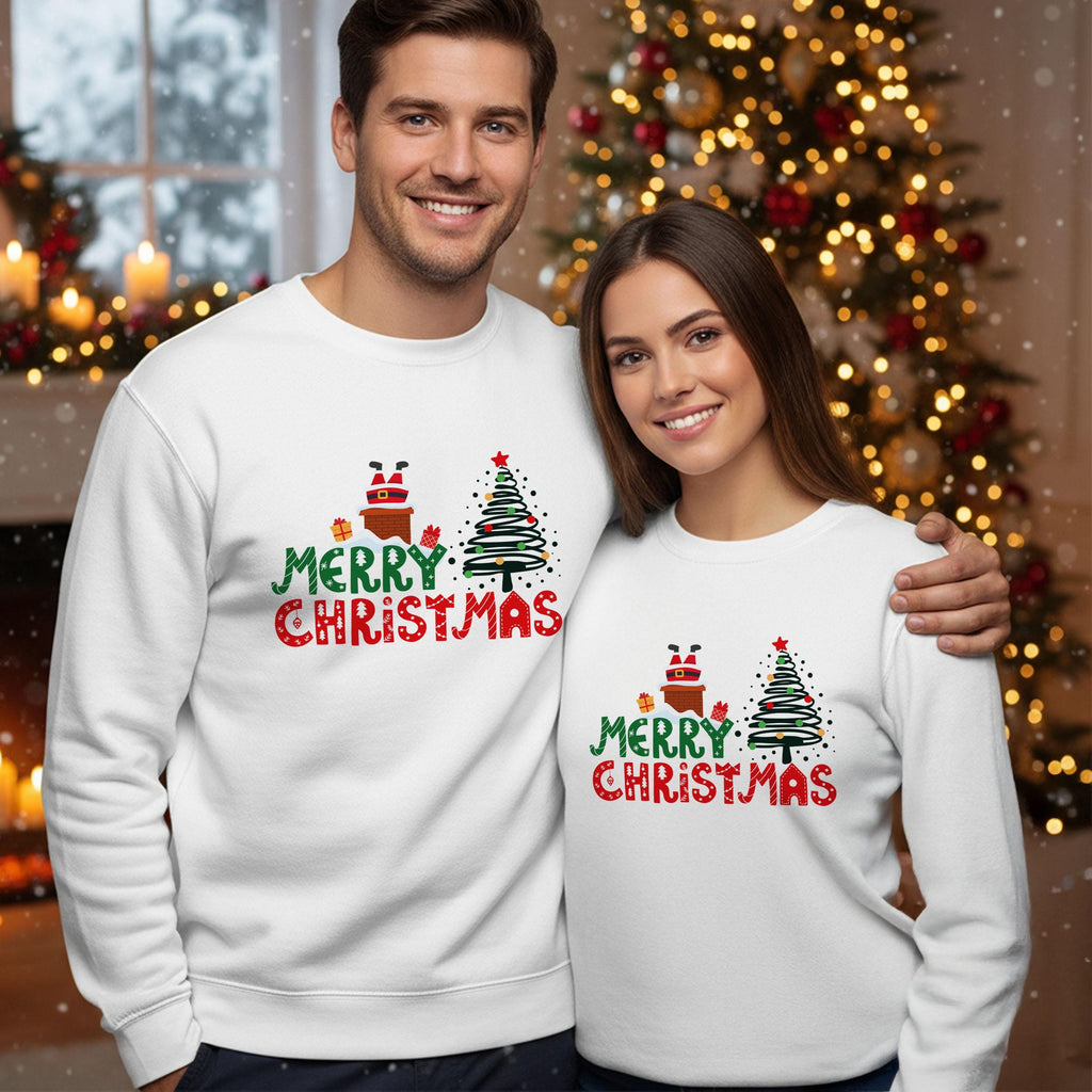 A man and a woman are standing together in front of a Christmas tree, both wearing matching white sweatshirts with the text &quot;Merry Christmas&quot; printed on them.