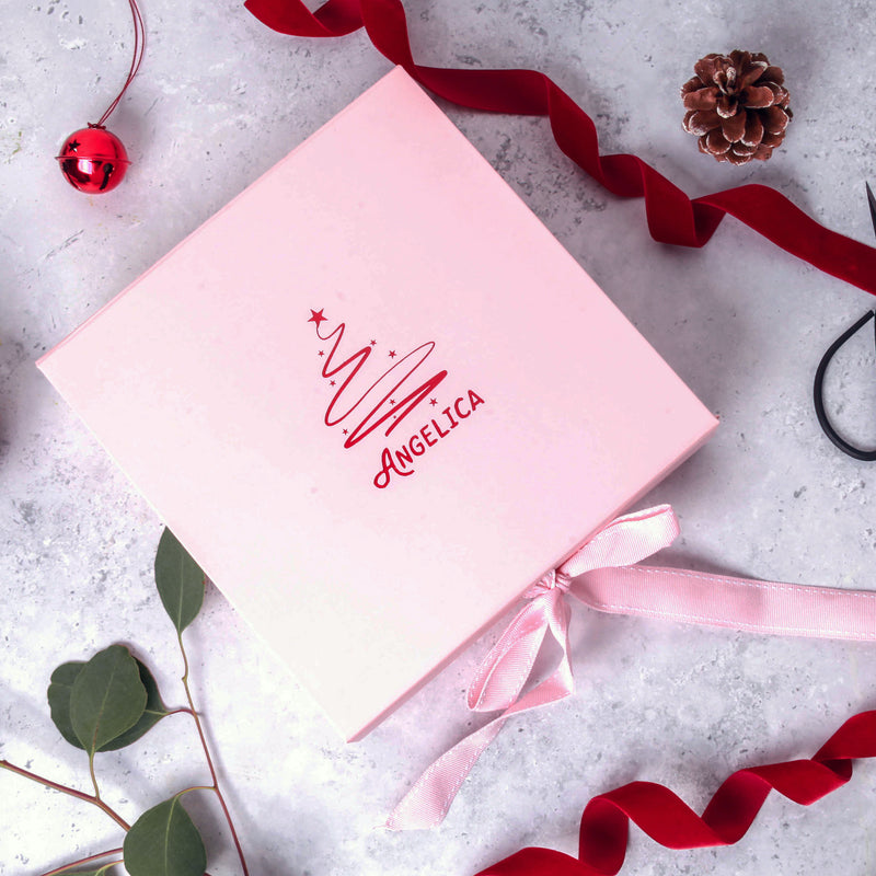 a pink box with a red ribbon and a pine cone