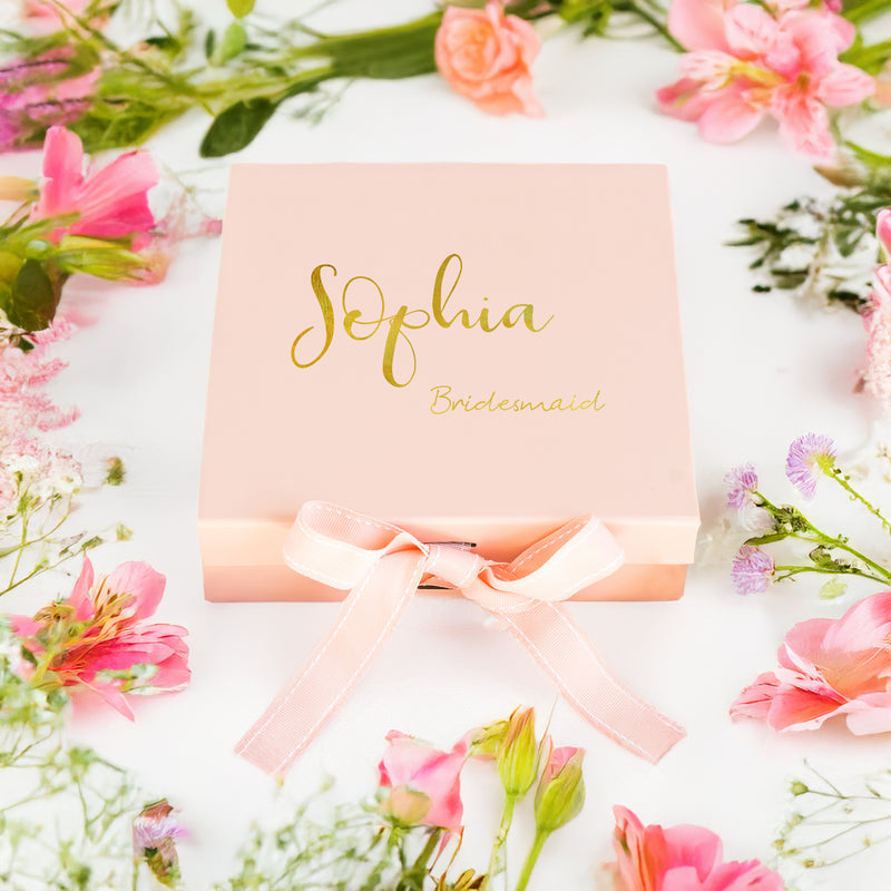 a pink box with a name on it surrounded by flowers