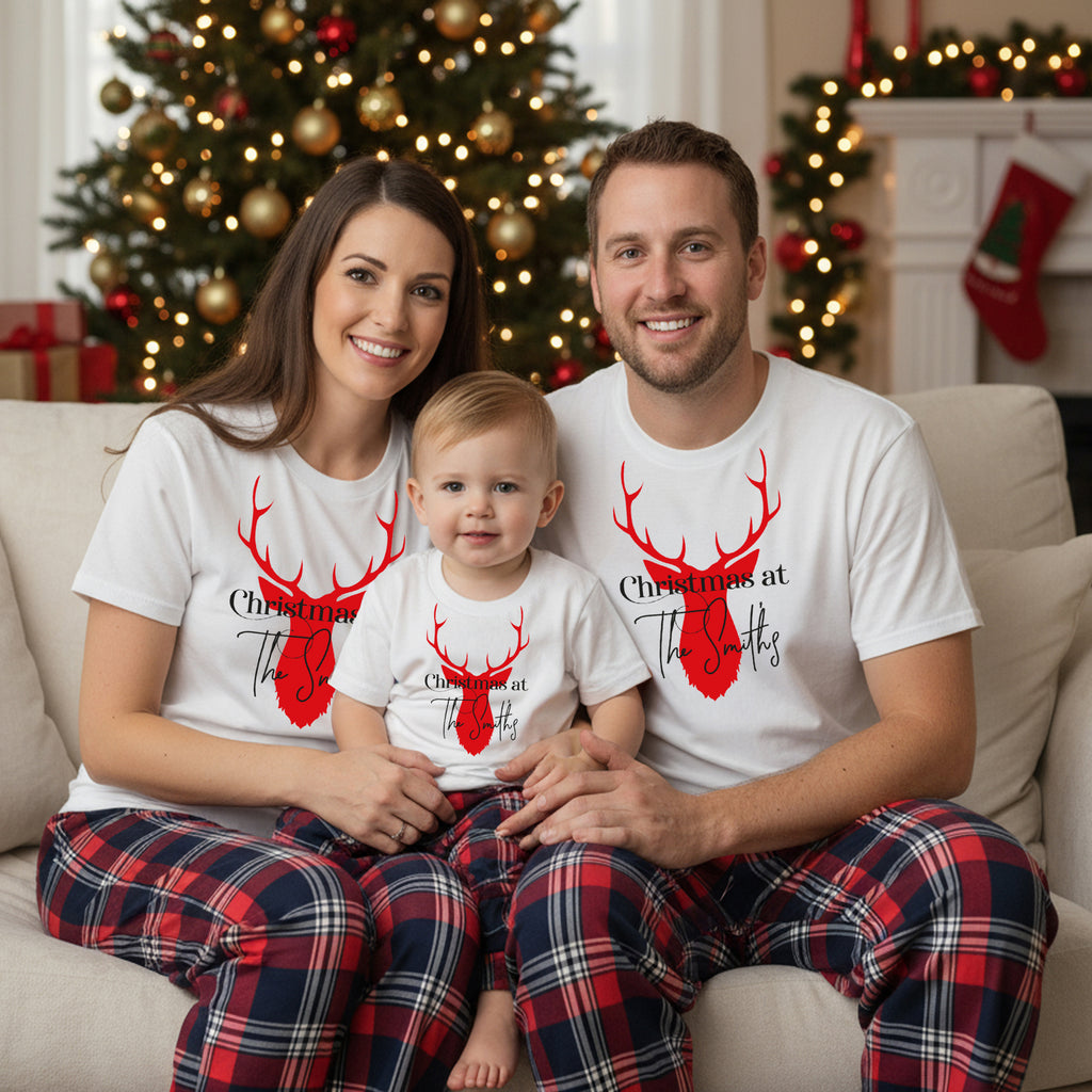 A happy family of three, consisting of a mother, father, and child, posing for a Christmas photo in front of a decorated Christmas tree.
