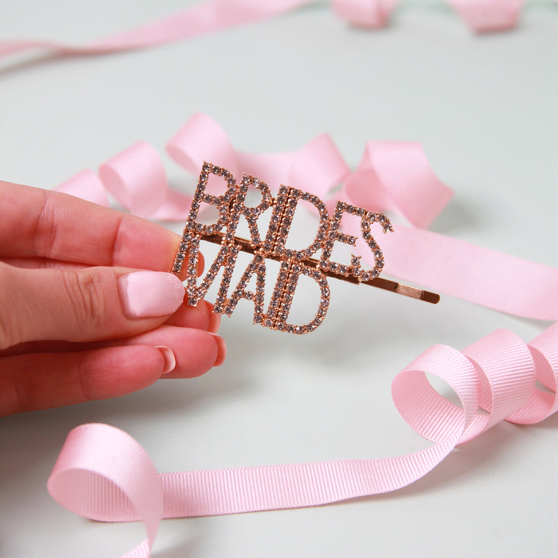 a person holding a pink ribbon and a bride's hair pin