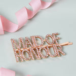 a pair of pink hair clips with the word bride on them