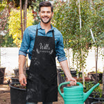a man in an apron holding a green watering can