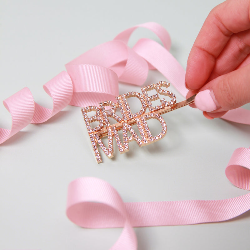 a person is holding a pink ribbon and a brooch
